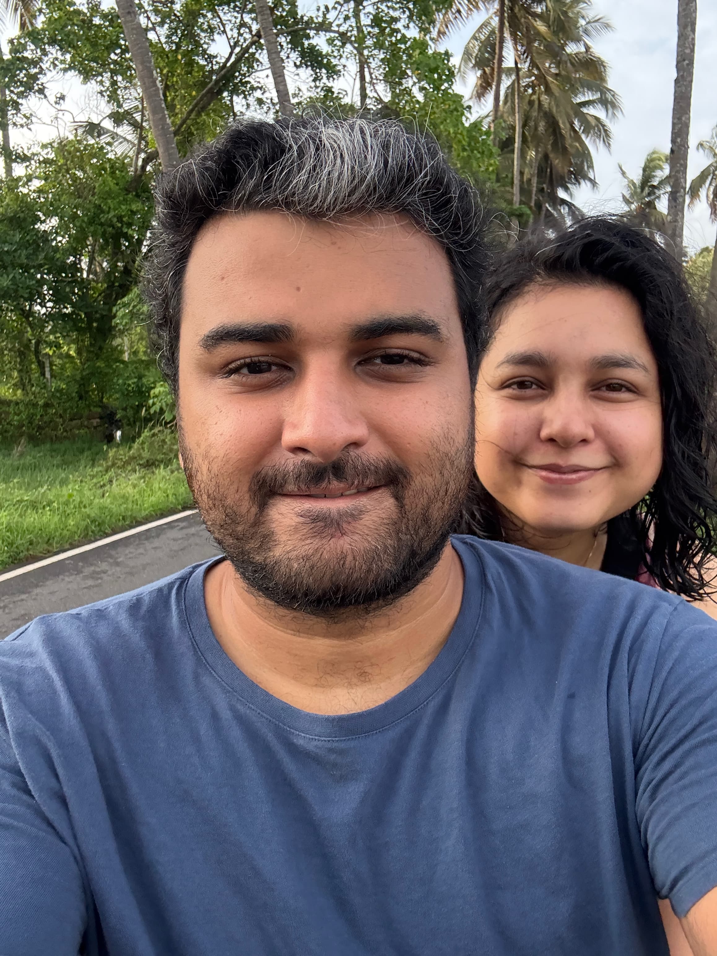 Sanchita and Garvit on a quiet Goan road, palm trees behind them